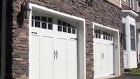 two white garage doors in front of a house